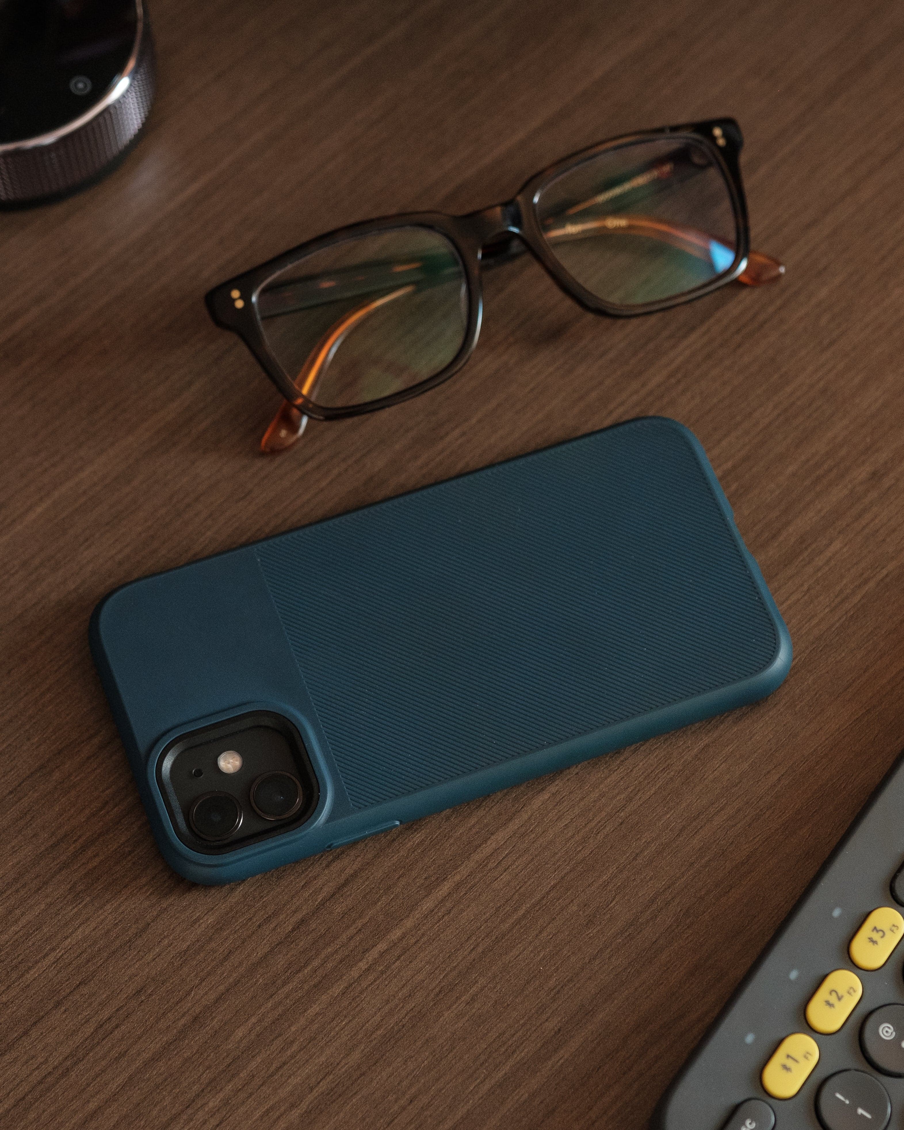 Blue phone case and eyeglasses on wooden table